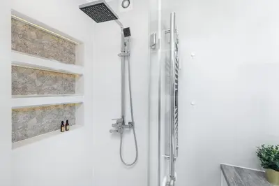 a shower with a shower head in a bathroom at Sunny Kliny Apartment in Kraków