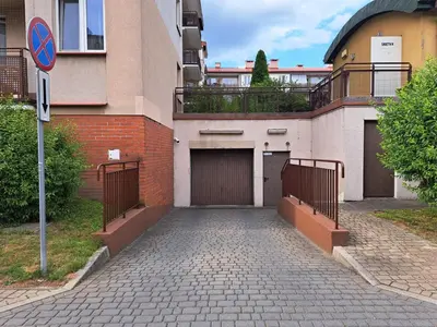 a building with two garage doors and a gate at Sunny Kliny Apartment in Kraków