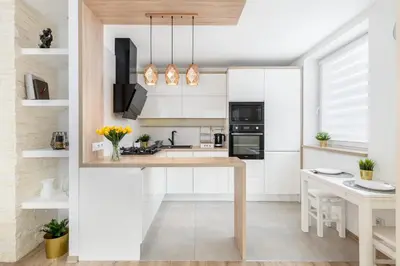 a kitchen with white cabinets and a wooden table at Sunny Kliny Apartment in Kraków