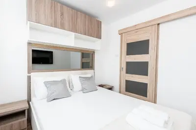a bedroom with a white bed and a window at Sunny Kliny Apartment in Kraków
