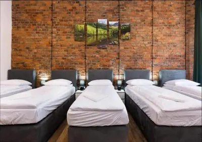 a room with four beds against a brick wall at Spacious City Center Family Apartments in Kraków