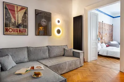 a living room with a gray couch and a bed at Spacious City Center Family Apartments in Kraków