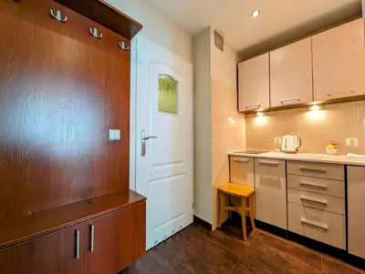 a kitchen with wooden cabinets and a white door at Kazimierza Wielkiego 87 by Homeprime in Kraków