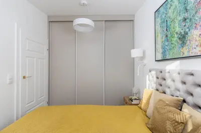 a bedroom with a yellow bed and a painting on the wall at Mostowa Street by Tyzenhauz in Kraków