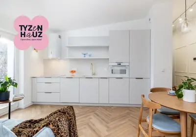a kitchen with white cabinets and a wooden table at Mostowa Street by Tyzenhauz in Kraków
