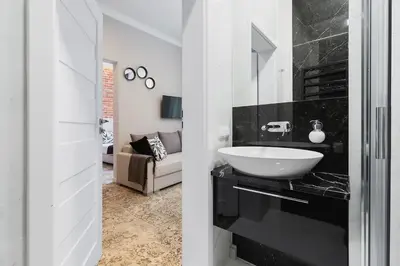 a black and white bathroom with a sink and a couch at Apartment with balcony - Rakowicka 6 Street in Kraków