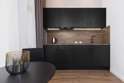 a kitchen with black cabinets and a table at Apartment with balcony - Rakowicka 6 Street in Kraków