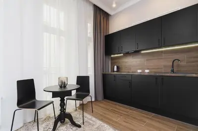 a kitchen with black cabinets and a table and chairs at Apartment with balcony - Rakowicka 6 Street in Kraków