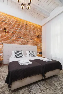 a bedroom with a large bed with a brick wall at Apartment with balcony - Rakowicka 6 Street in Kraków