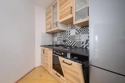 a small kitchen with wooden cabinets and a refrigerator at 3 bedroom apartment-Aleja Daszyńskiego- Grzegórzki in Kraków