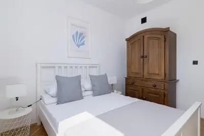 a bedroom with a white bed and a wooden cabinet at 3 bedroom apartment-Aleja Daszyńskiego- Grzegórzki in Kraków