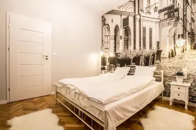 a bed in a room with a painting of a street at 1-bedroom apartment - Kazimierz- Starowiślna 54 in Kraków