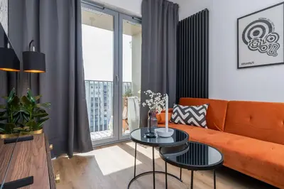 a living room with an orange couch and a table at RentPlanet - Apartamenty Aura Prandoty in Kraków