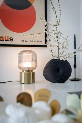 a table with a lamp and a vase of flowers at RentPlanet - Apartamenty Aura Prandoty in Kraków