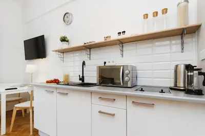 a kitchen with white cabinets and a microwave at Studio Apartment - Rzeszowska 4 Street in Kraków