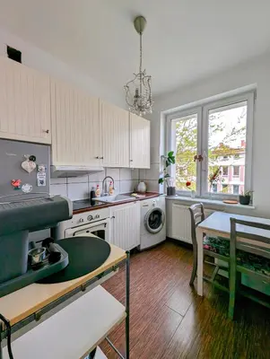 a kitchen with white cabinets and a table and a dining room at Urzędnicza 23 by Homeprime in Kraków