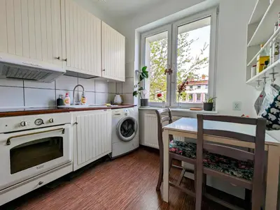 a kitchen with white cabinets and a table and a dishwasher at Urzędnicza 23 by Homeprime in Kraków