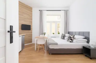 a white bedroom with a bed and a desk at Studio Apartment - Radziwiłłowska 27 in Kraków