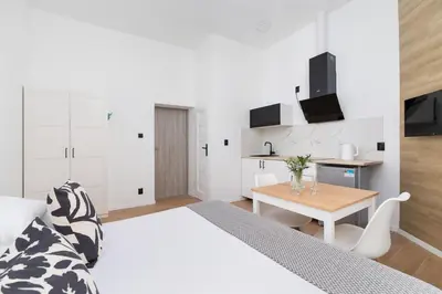 a white bedroom with a bed and a table at Studio Apartment - Radziwiłłowska 27 in Kraków
