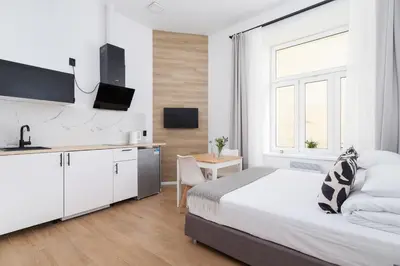 a white bedroom with a bed and a kitchen at Studio Apartment - Radziwiłłowska 27 in Kraków