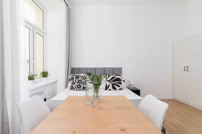a dining room with a wooden table with white chairs at Studio Apartment - Radziwiłłowska 27 in Kraków