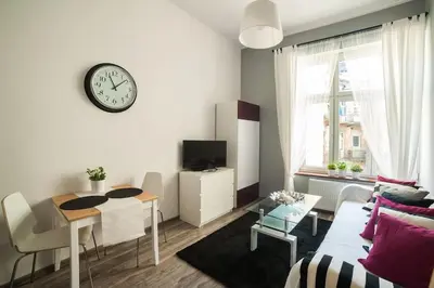 a living room with a table and a clock on the wall at Apartment in the centre - Old Town in Kraków