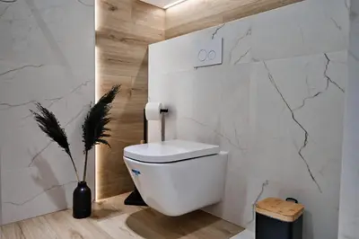 a white toilet in a bathroom with a marble wall at Apartament Mars by Housine in Zator
