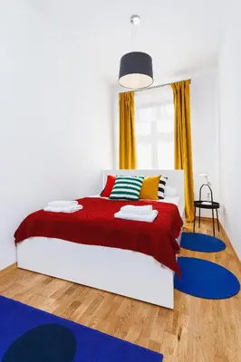 a bedroom with a large bed with red and blue rugs at Apartment for two Krakowska 16 Street in Kraków