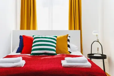 a bed with colorful pillows and a red blanket at Apartment for two Krakowska 16 Street in Kraków