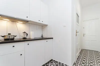a kitchen with white cabinets and a tile floor at Apartment for two Krakowska 16 Street in Kraków