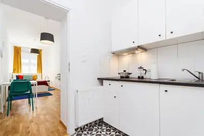 a kitchen with white cabinets and a blue chair at Apartment for two Krakowska 16 Street in Kraków