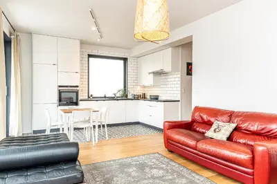 a living room with a red leather couch and a kitchen at RentPlanet - Kamienica Retmana in Kraków