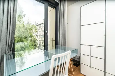 a glass table and a chair in a room with a window at RentPlanet - Kamienica Retmana in Kraków