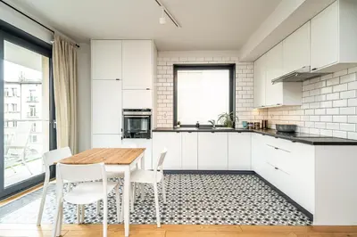 a kitchen with white cabinets and a wooden table and chairs at RentPlanet - Kamienica Retmana in Kraków