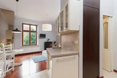 a kitchen with white cabinets and a dining room at Main Square Apartment - Old Town in Kraków