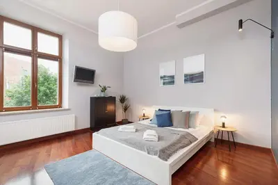 a white bedroom with a bed and a large window at Main Square Apartment - Old Town in Kraków