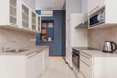 a kitchen with white cabinets and a sink and a microwave at Main Square Apartment - Old Town in Kraków