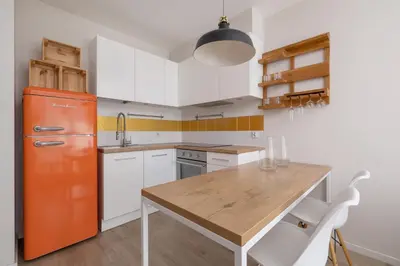 an orange refrigerator in a kitchen with a wooden table at Apartment with Balcony - Masarska 8 Street in Kraków