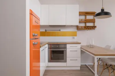 a kitchen with white cabinets and a wooden table at Apartment with Balcony - Masarska 8 Street in Kraków