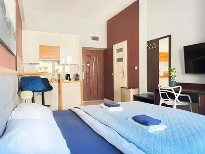 a bedroom with a blue bed and a kitchen at Well-connected Apartment in Old Town Cracow in Kraków