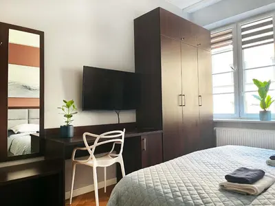a bedroom with a bed and a desk and a mirror at Well-connected Apartment in Old Town Cracow in Kraków