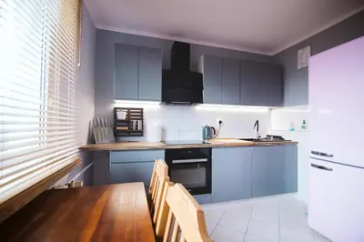 a kitchen with blue cabinets and a wooden table at Dwupokojowy Apartament 700 m od Szpital Prokocim in Kraków
