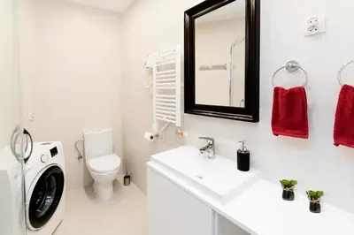 a white bathroom with a washing machine and a sink at Jewish Quarter - 54 Starowiślna Street in Kraków