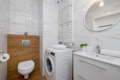 a white bathroom with a washing machine and a sink at Stylish Apartment near Tauron Arena by Rent like home in Kraków