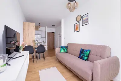 a living room with a couch and a kitchen at Stylish Apartment near Tauron Arena by Rent like home in Kraków