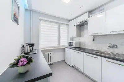 a kitchen with white cabinets and a vase of flowers on a counter at APARTAMENT PARKOWY UL. RACLAWICKA in Kraków
