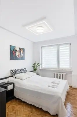 a white bedroom with a large bed and a window at APARTAMENT PARKOWY UL. RACLAWICKA in Kraków