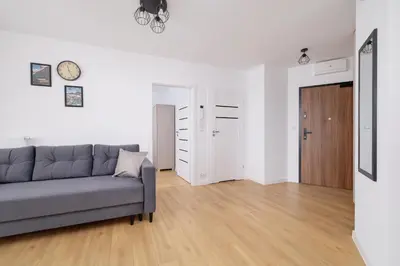 a living room with a couch and a wooden floor at Modern Apartment with Parking near Tauron Arena by Rent like home in Kraków