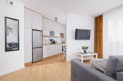 a living room with a couch and a kitchen at Modern Apartment with Parking near Tauron Arena by Rent like home in Kraków