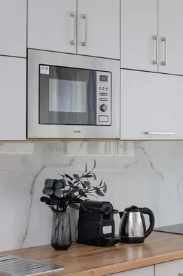 a kitchen with a microwave and a vase with flowers at Modern Apartment with Parking near Tauron Arena by Rent like home in Kraków